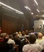 En la imagen vemos decenas de participantes en el congreso y una mesa principal con expositores al fondo