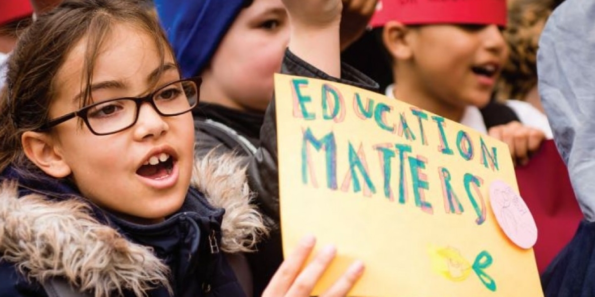Una niña sostiene un cartel en una manifestación que indica "La educación importa"
